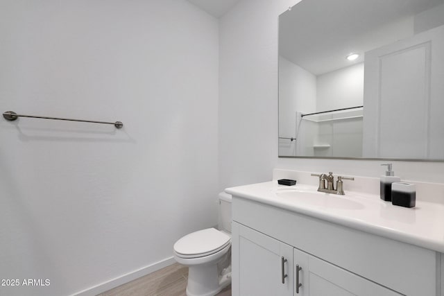 bathroom with toilet, wood finished floors, a shower, baseboards, and vanity