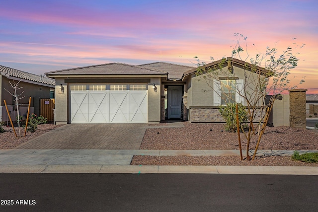 view of front of property featuring solar panels, a tile roof, stucco siding, decorative driveway, and an attached garage