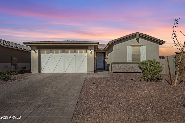 view of front of home with stucco siding, an attached garage, decorative driveway, and fence