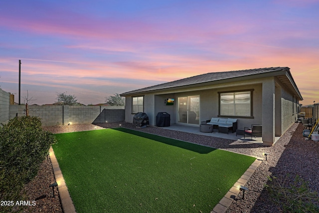 back of property at dusk featuring outdoor lounge area, a patio area, a fenced backyard, and stucco siding