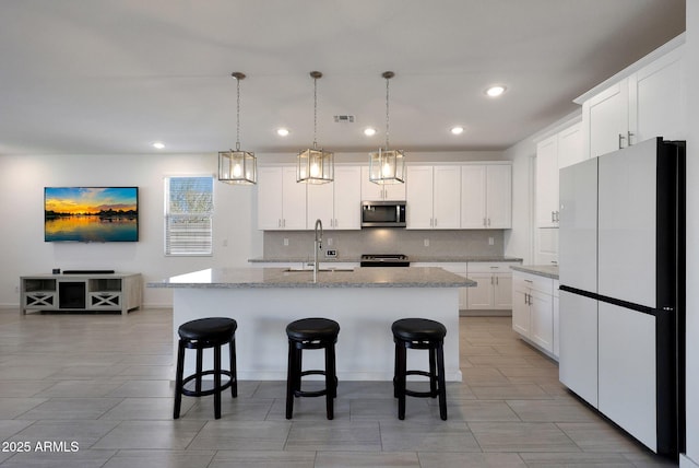 kitchen featuring visible vents, a kitchen breakfast bar, backsplash, and appliances with stainless steel finishes