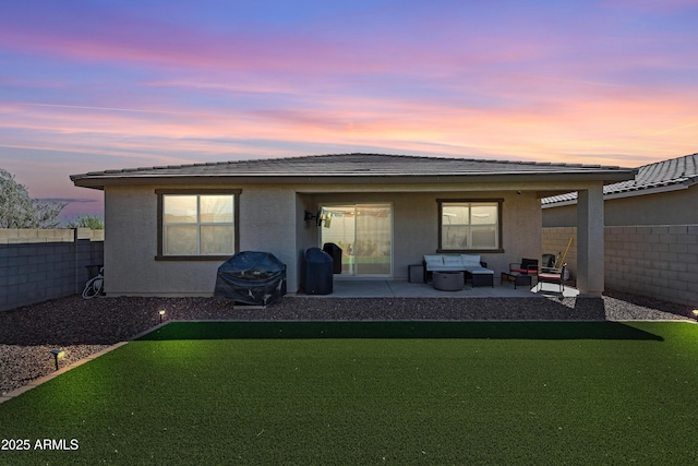 back of property featuring a patio, a fenced backyard, stucco siding, outdoor lounge area, and a lawn