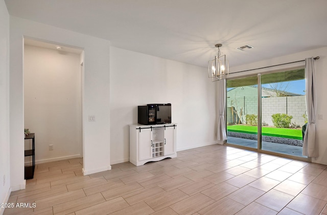 interior space featuring baseboards, visible vents, and a chandelier