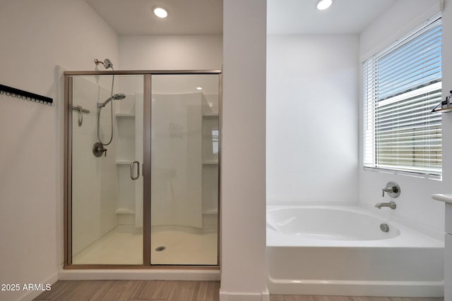 bathroom featuring a shower stall, a bath, wood finished floors, and recessed lighting