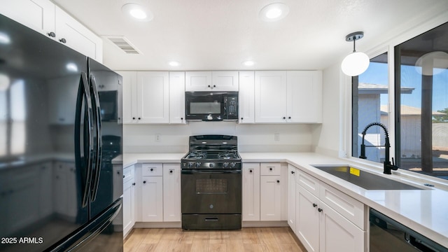 kitchen with black appliances, decorative light fixtures, and white cabinetry