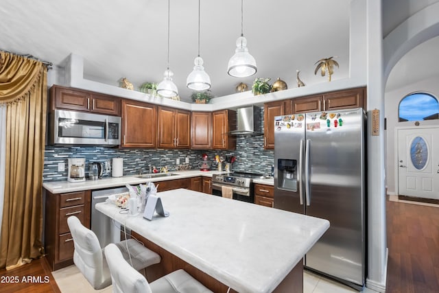 kitchen with appliances with stainless steel finishes, a center island, wall chimney range hood, tasteful backsplash, and sink