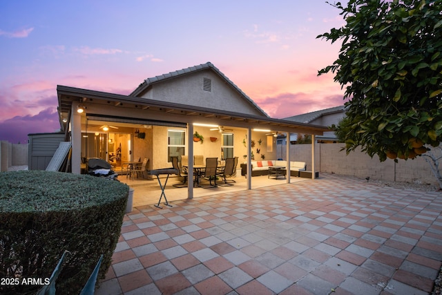 back house at dusk with a patio area and outdoor lounge area