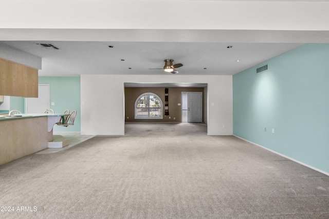 unfurnished living room featuring ceiling fan and light colored carpet