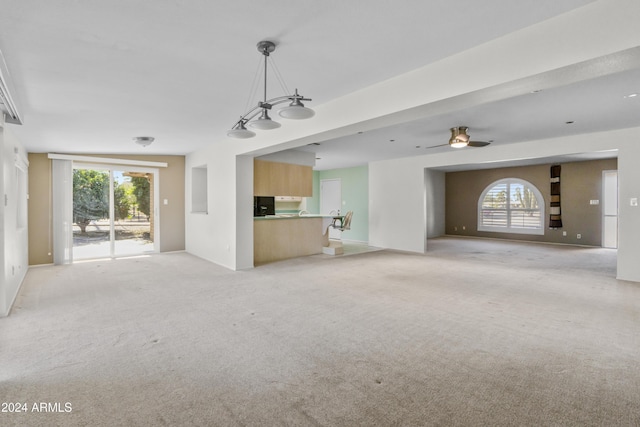 unfurnished living room featuring ceiling fan and light colored carpet