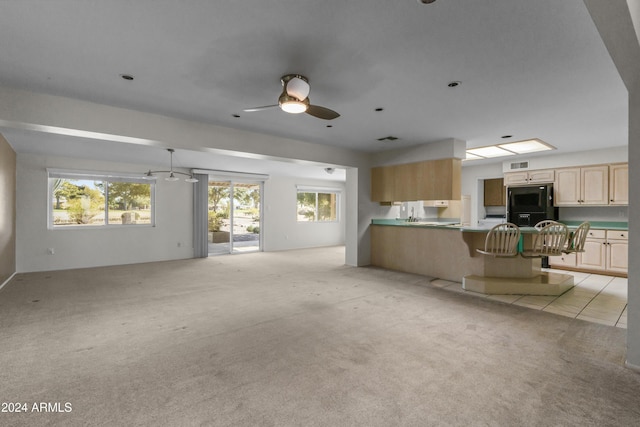 unfurnished living room featuring light colored carpet and ceiling fan