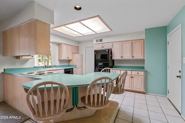 kitchen with black appliances, light tile patterned floors, kitchen peninsula, and light brown cabinetry