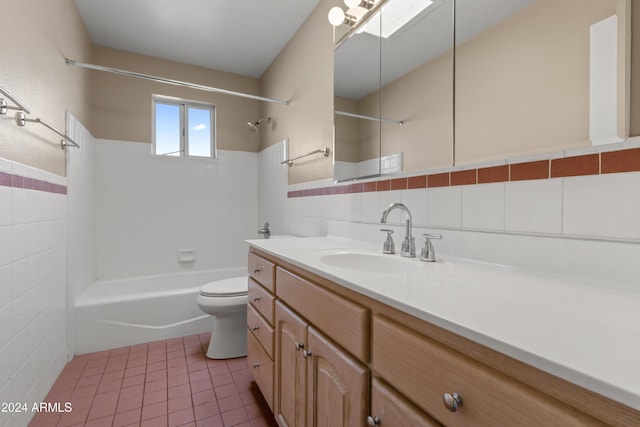 full bathroom with tile patterned flooring, vanity, a skylight, and tile walls