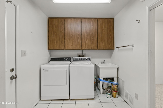 washroom featuring cabinets, light tile patterned floors, and washing machine and clothes dryer