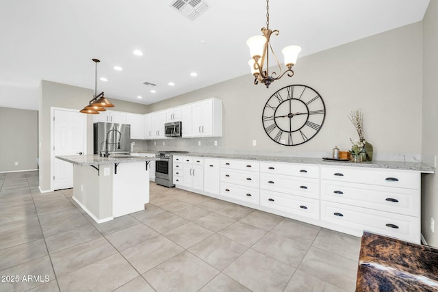 kitchen with light tile patterned floors, appliances with stainless steel finishes, white cabinetry, hanging light fixtures, and light stone counters