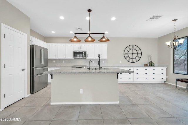 kitchen with light stone counters, pendant lighting, stainless steel appliances, and white cabinets