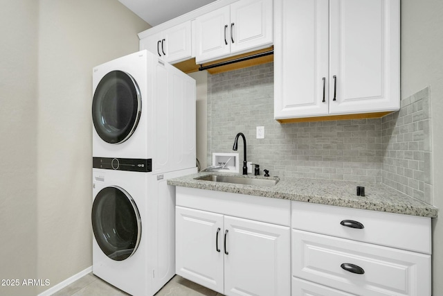 washroom with sink, cabinets, and stacked washer and clothes dryer