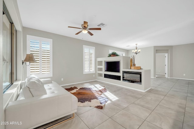 tiled living room with ceiling fan with notable chandelier