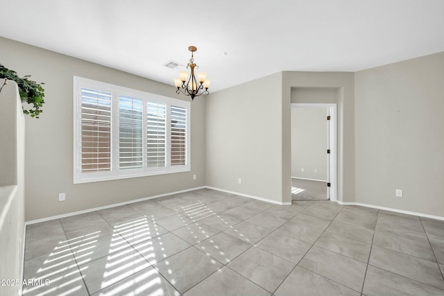 tiled spare room with an inviting chandelier