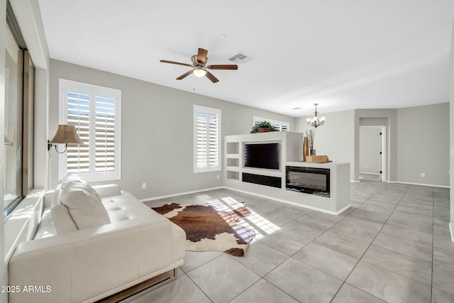 living room featuring light tile patterned floors and ceiling fan with notable chandelier