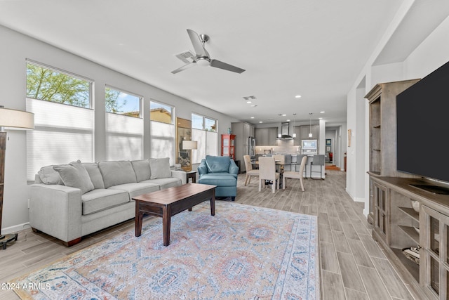 living room featuring light hardwood / wood-style flooring, ceiling fan, and a healthy amount of sunlight