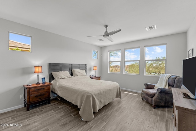 bedroom with multiple windows, ceiling fan, and light hardwood / wood-style flooring