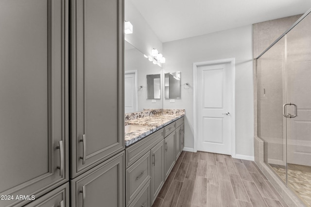 bathroom with hardwood / wood-style floors, a shower with shower door, and vanity