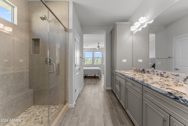 bathroom featuring ceiling fan, a shower with shower door, and vanity