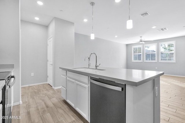 kitchen featuring appliances with stainless steel finishes, decorative light fixtures, sink, white cabinets, and a center island with sink