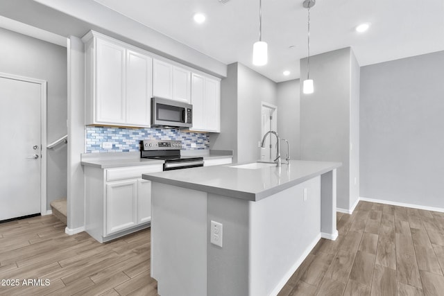 kitchen featuring white cabinetry, stainless steel appliances, and decorative light fixtures