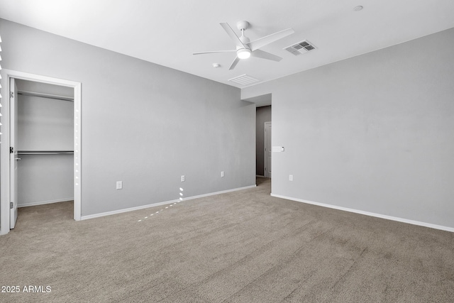 unfurnished bedroom with a walk in closet, a closet, ceiling fan, and carpet flooring