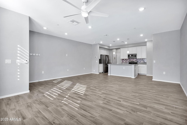 unfurnished living room with ceiling fan and light hardwood / wood-style flooring