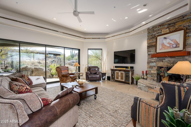 living room featuring a stone fireplace, ceiling fan, and light tile patterned flooring