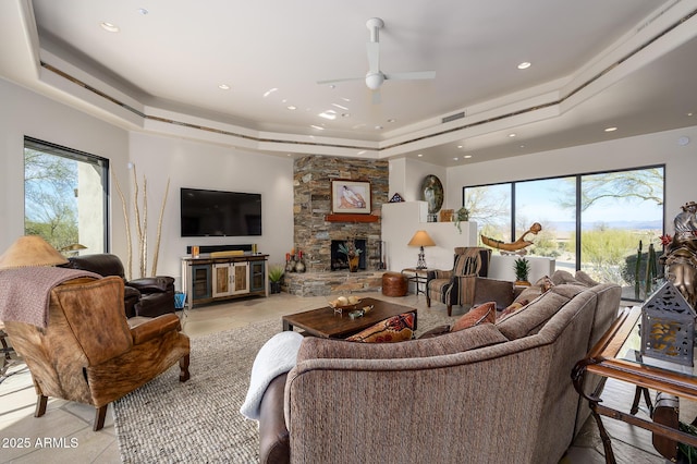 living room featuring a fireplace, a healthy amount of sunlight, and a tray ceiling