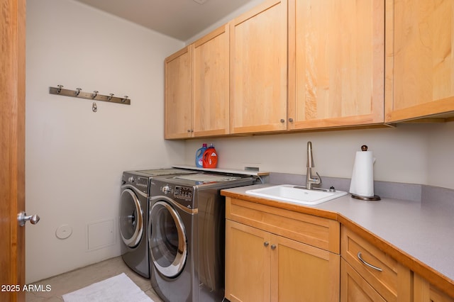 clothes washing area featuring cabinets, sink, and washer and dryer