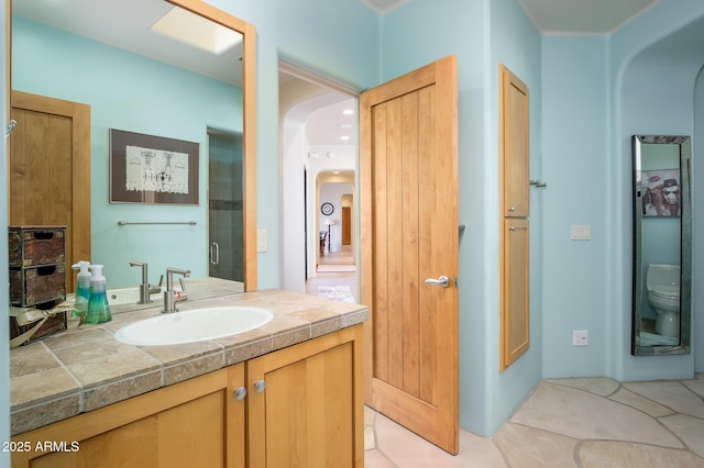 bathroom with vanity, a shower with shower door, tile patterned floors, and toilet