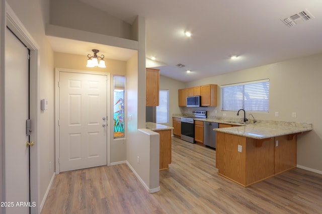 1563 E Peregrine Trl, Casa Grande, AZ 85122 - kitchen with stainless steel appliances, a sink, a peninsula, light wood-style floors, and baseboards