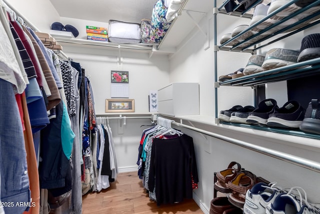 walk in closet with light hardwood / wood-style floors