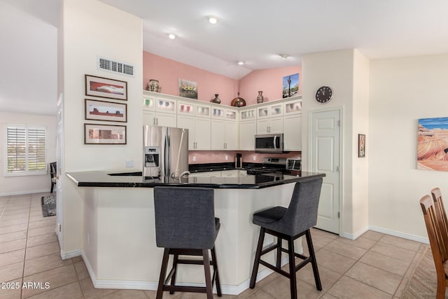 kitchen featuring stainless steel appliances, white cabinetry, a breakfast bar area, and light tile patterned flooring