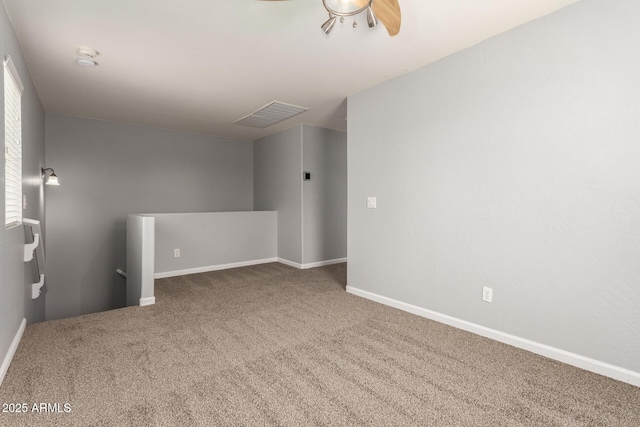 carpeted spare room with baseboards, ceiling fan, and visible vents