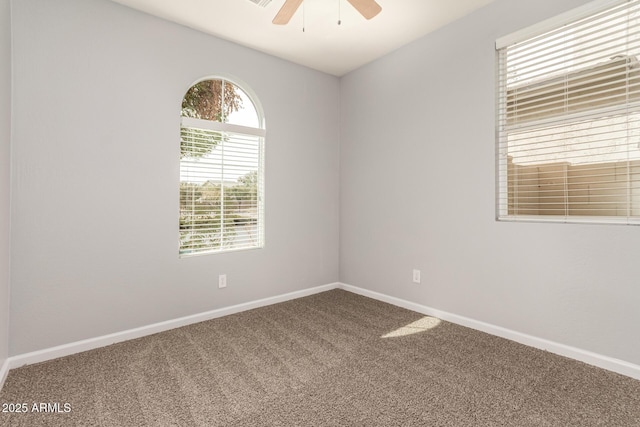 carpeted spare room featuring baseboards and ceiling fan