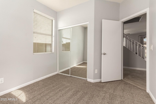 unfurnished bedroom featuring a closet, carpet flooring, baseboards, and tile patterned flooring