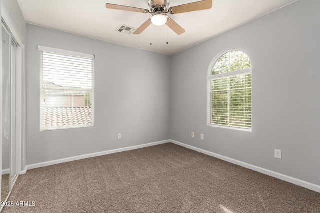 empty room featuring baseboards, a ceiling fan, visible vents, and carpet