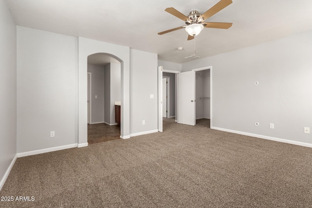 unfurnished bedroom featuring a ceiling fan, baseboards, visible vents, arched walkways, and carpet