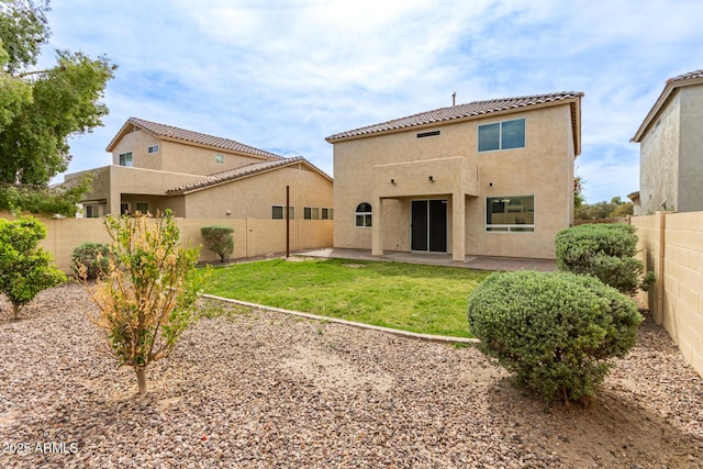 back of house with a fenced backyard, a lawn, stucco siding, and a patio