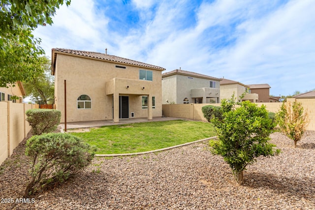rear view of property featuring a patio area, stucco siding, a fenced backyard, a tiled roof, and a yard
