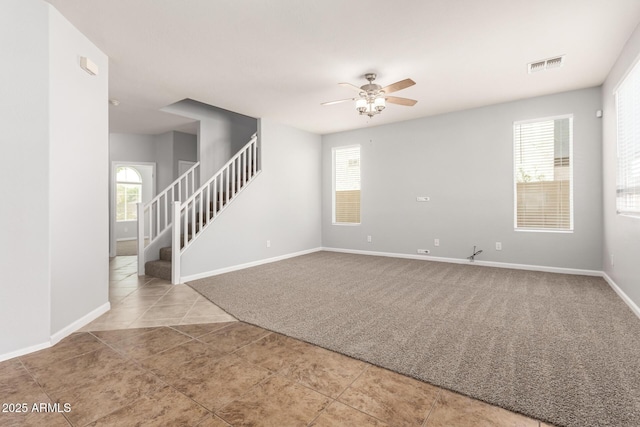 spare room with carpet floors, stairway, a ceiling fan, baseboards, and visible vents