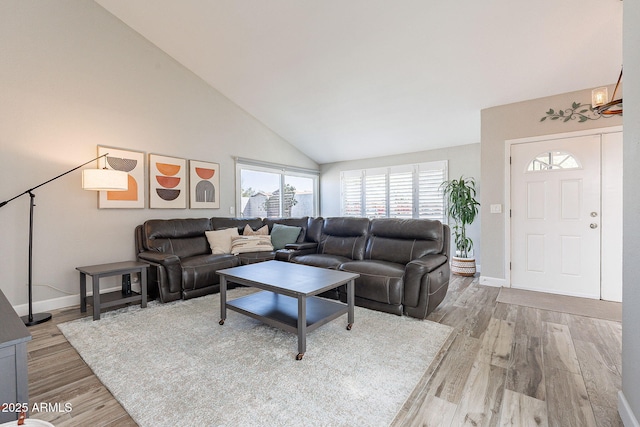 living room with high vaulted ceiling, baseboards, and wood finished floors