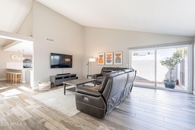 living room featuring wood finished floors, visible vents, and high vaulted ceiling