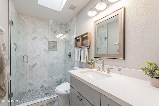 full bathroom featuring vanity, visible vents, a shower stall, toilet, and a textured wall