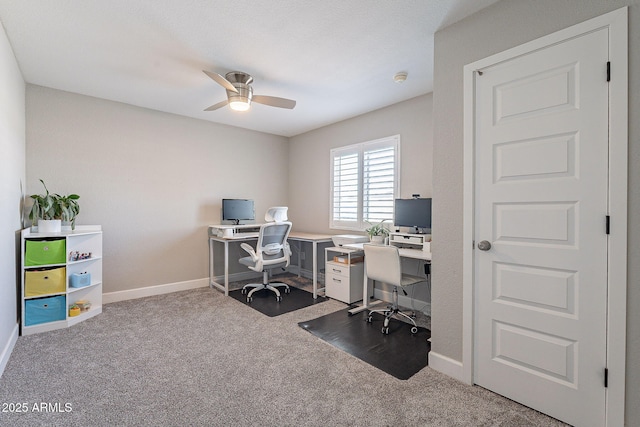 carpeted office space with a ceiling fan and baseboards